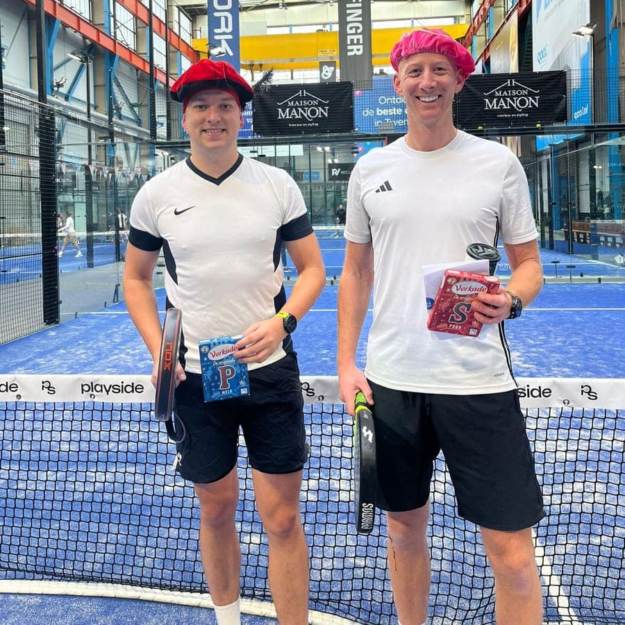 Twee spelers met pietenmutsen en een chocoladeletter, bij het net op een baan van Playside